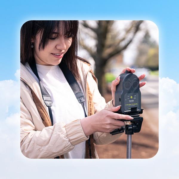 Estudante usando o sensor Go Direct Air Quality na beira de uma via para medir poluentes do ar